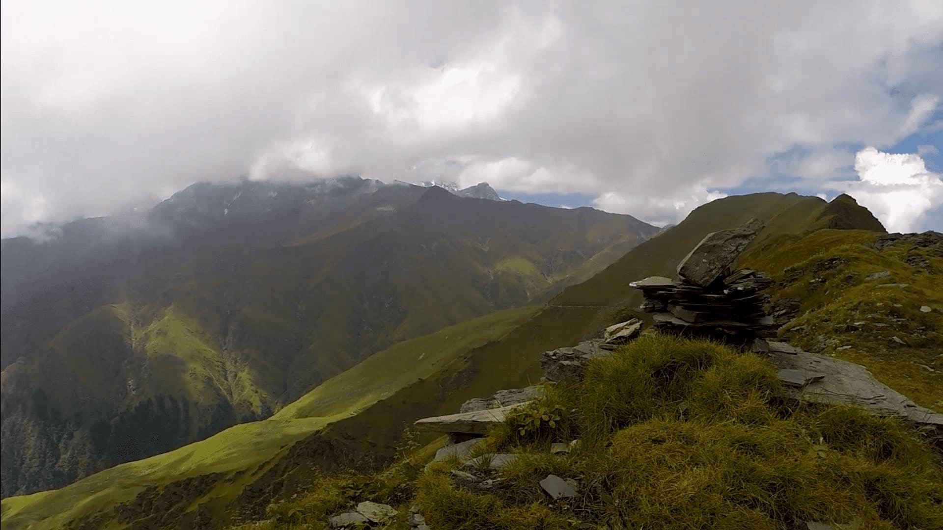 ループクンドへ向かう道の草の尾根と雲のかかった山