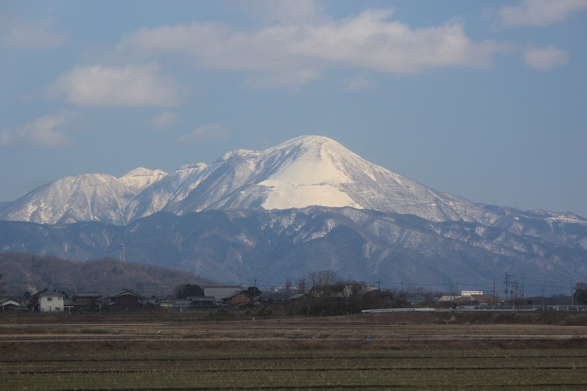 雪をかぶった伊吹山。手前に田と集落