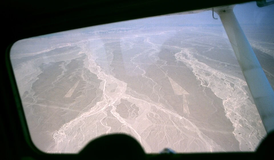 航空機の窓越しに見たナスカ台地の明るい直線と周囲の扇状地