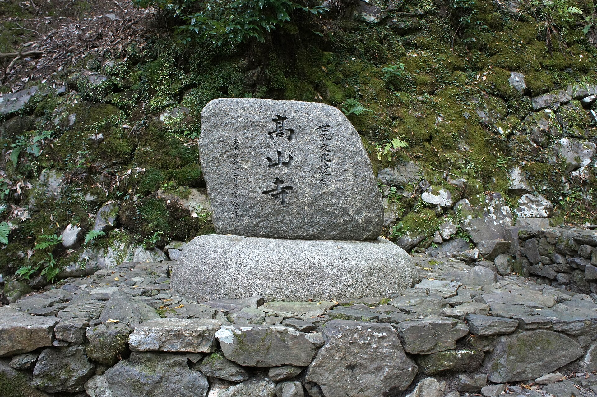 苔むした石垣の前に立つ「高山寺」の石標