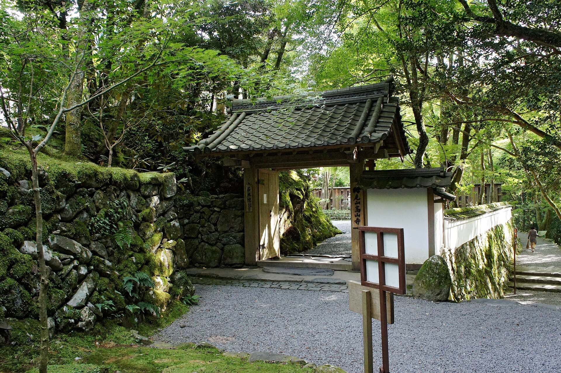 石水院の表門。白壁と瓦屋根の門、脇に木の立て札