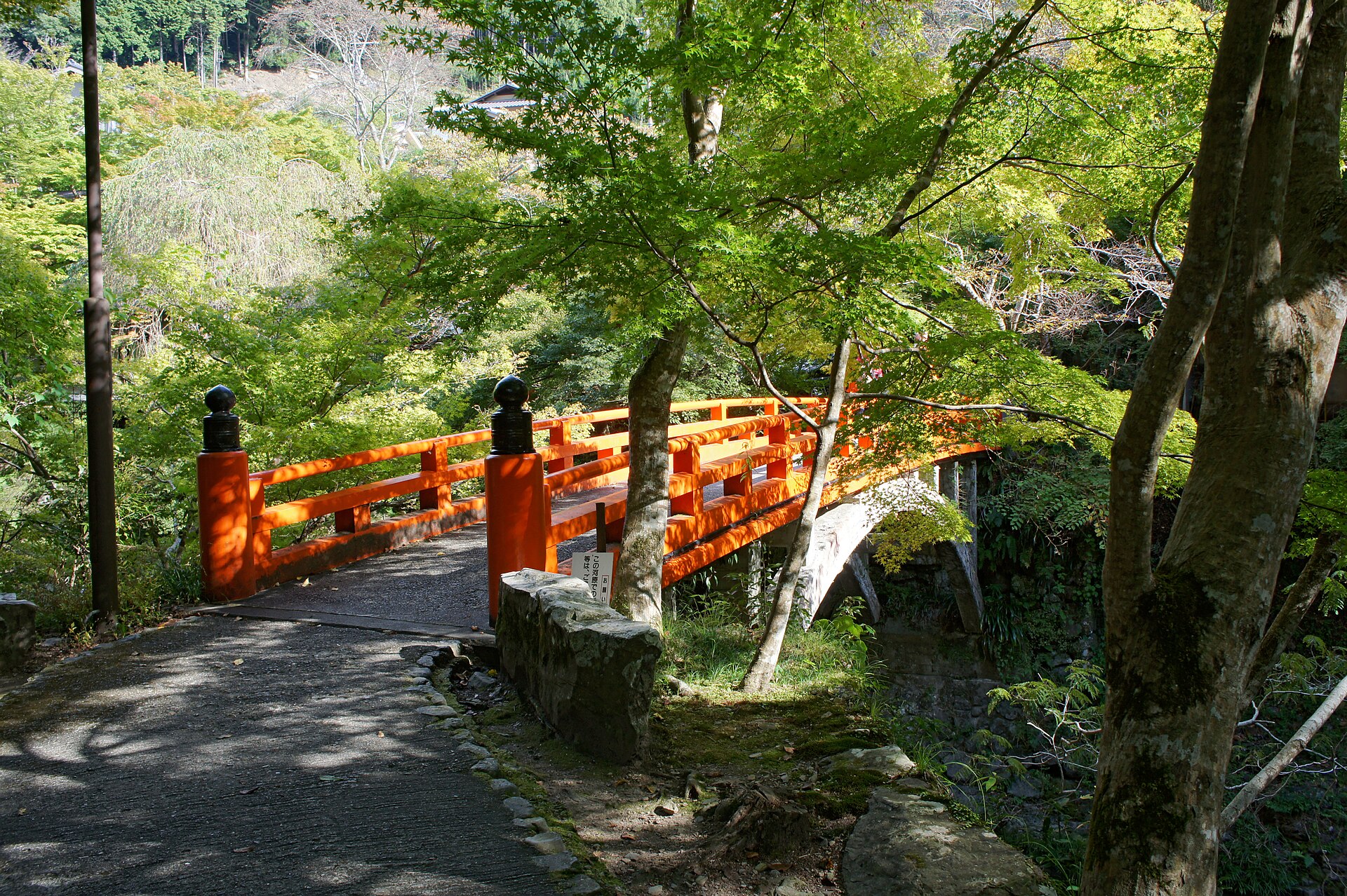 西明寺の指月橋。朱色の欄干の橋が谷川を渡り、砂利道が続く